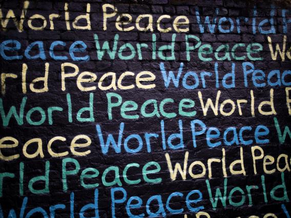 a splash screen of world peace written out in yellow, blue and green on a black background